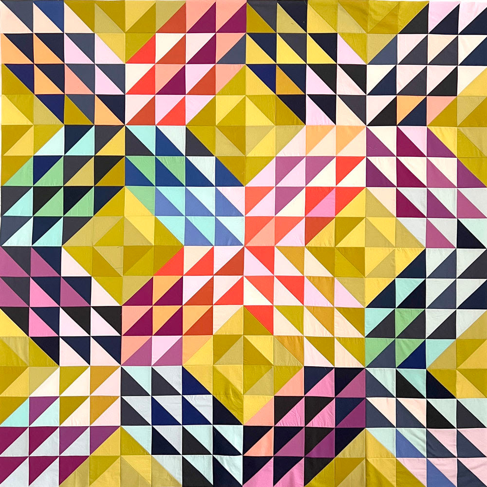 patchwork quilt kit made of colourful triangles in solid fabrics.  The background is yellow green and the design creates criss cross patterns